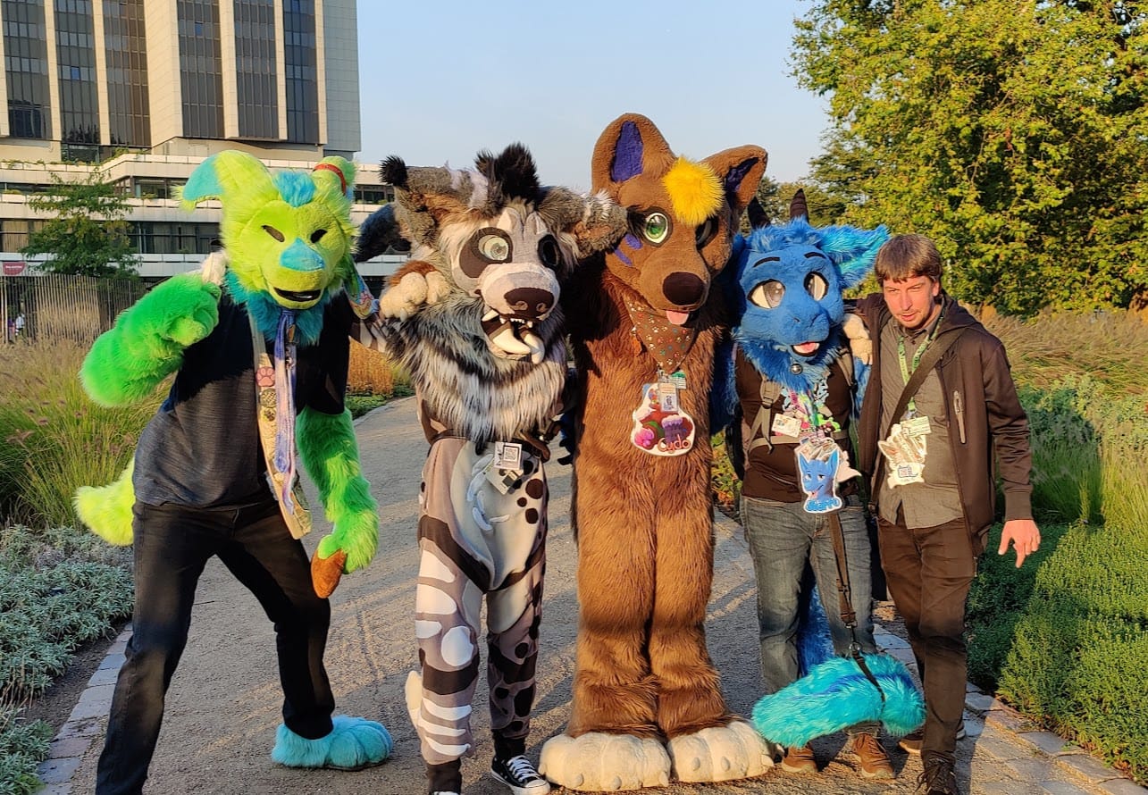 A group picture with 4 fursuiters and one person.