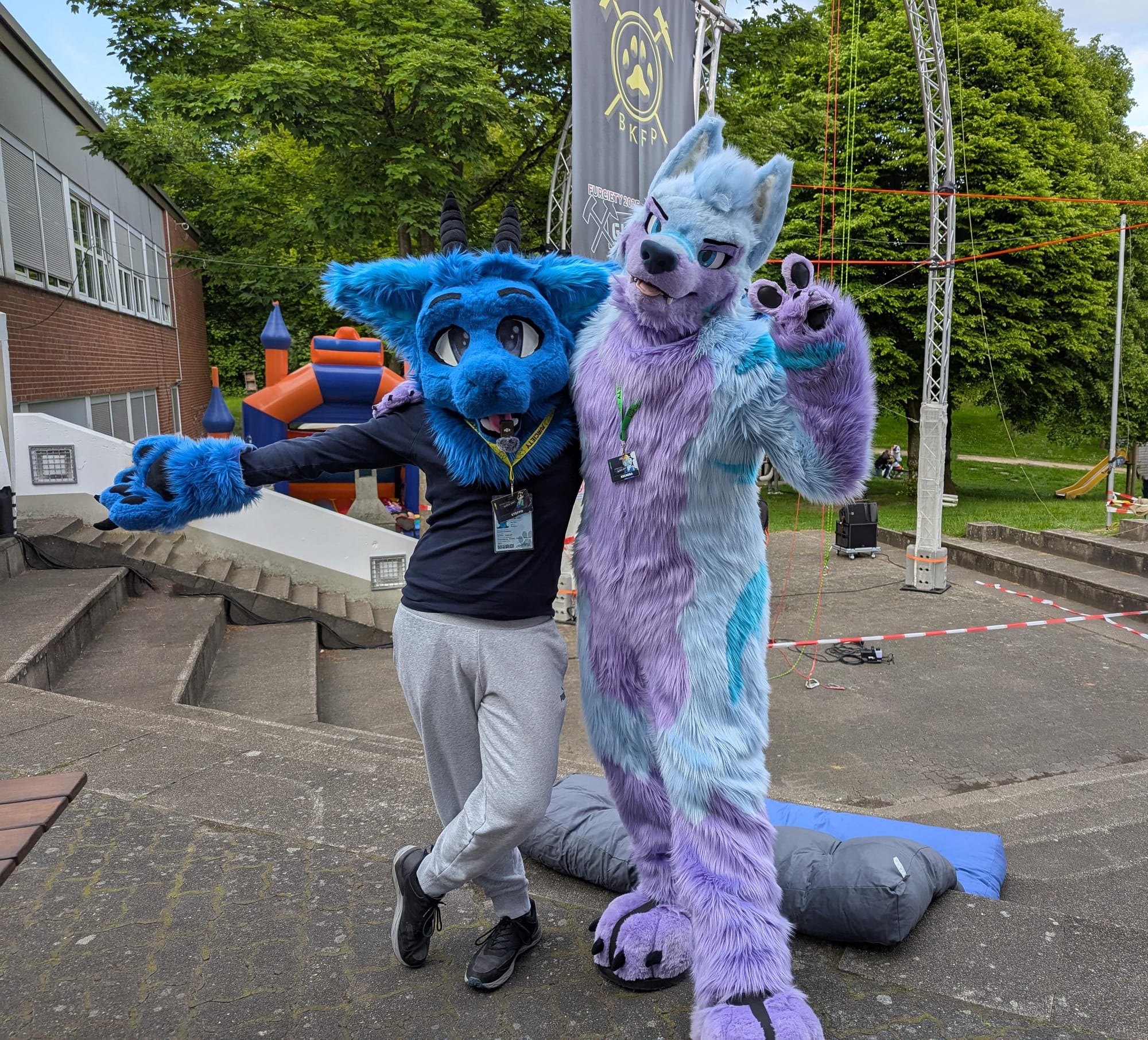 Ein Foto mit mir in meinem blauen, partial Drachen-Fursuit neben Keenora (in seinem Fullsuit). Wir schauen beide in die Kamera.