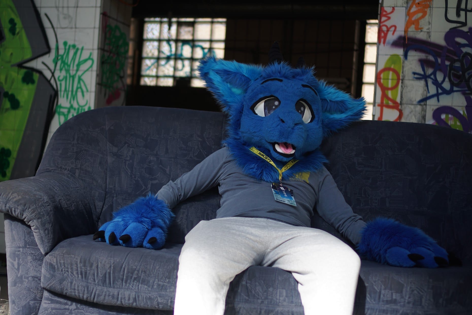 Ein Foto von mir im Fursuit, wie ich gechillt auf einer Couch in der Zeche sitze.